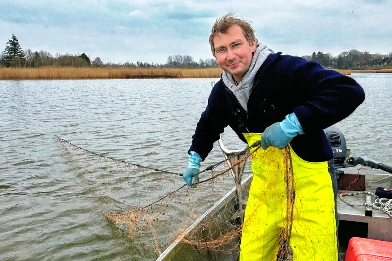Marcus Wöster aus seinem Kutter und holt ein Fischernetz ein 