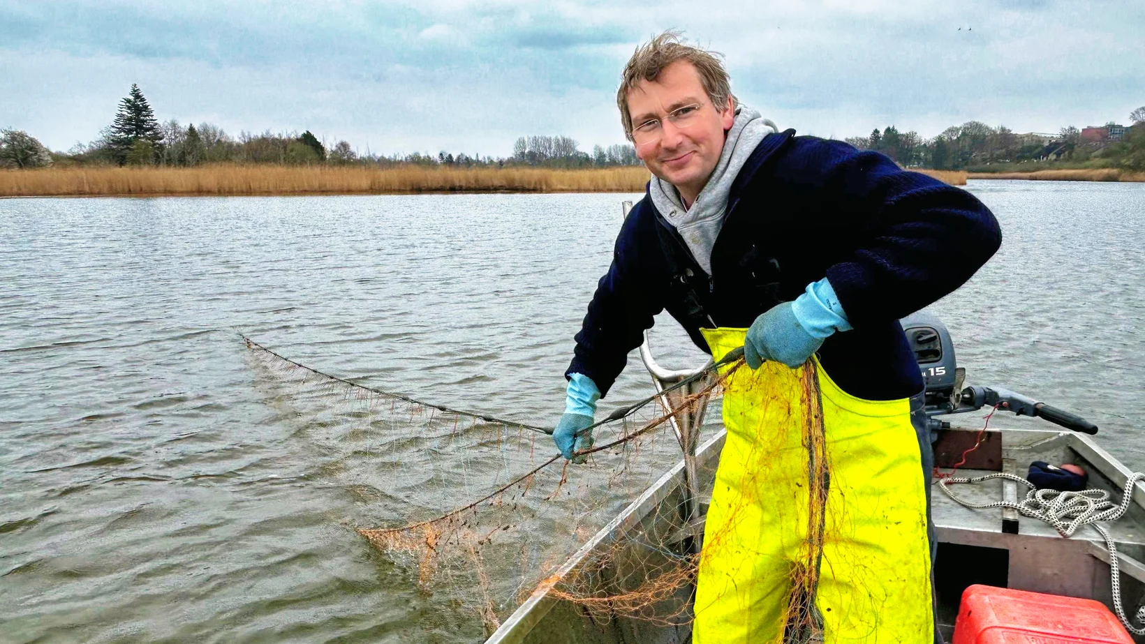 Marcus Wöster aus seinem Kutter und holt ein Fischernetz ein